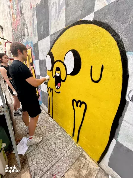 Da Nang graffiti art workshop: attendee spraying a giant yellow character on a corridor wall, hosted by Go Surfing