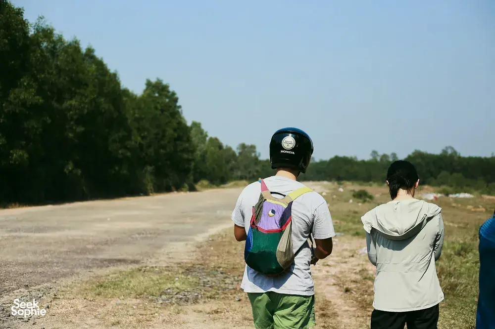 Motorbike road trip in rural Vietnam: two helmeted travellers on a quiet track near Hoi An during the waterfall adventure