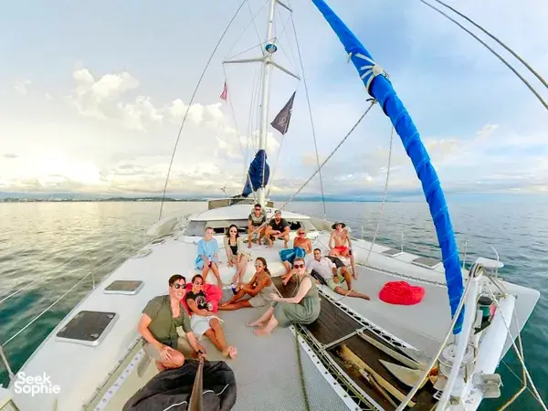 On SY Mawali, a group enjoys the open deck with a blue sail set during a private sunset yacht sail from Kota Kinabalu