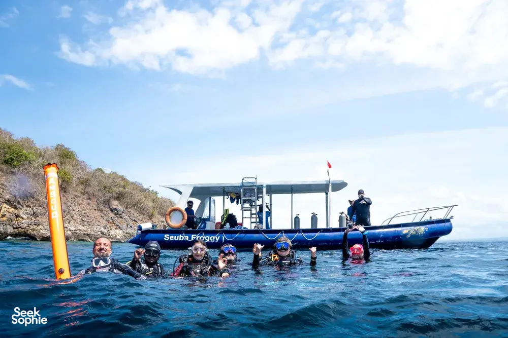 Divers bobbing in the sea beside a dive boat during Lombok Pink Beach 2 Fun Dives in Lombok under a bright sky