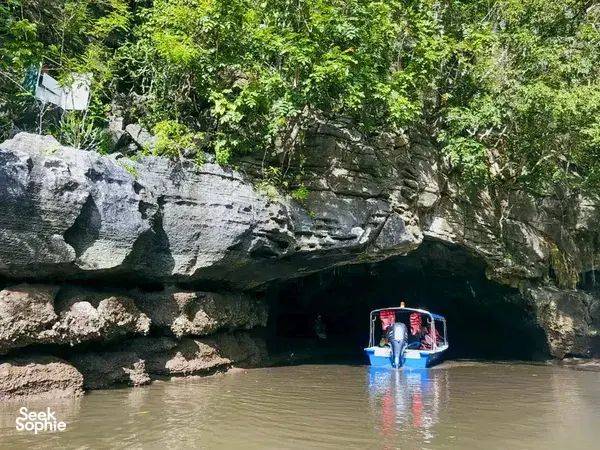 Small boat passing under limestone cliffs in Langkawi’s Tanjung Rhu UNESCO Geopark on a naturalist-guided cruise