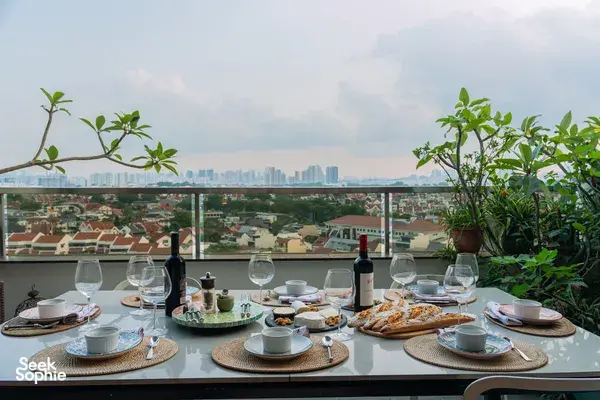 Balcony table set with wine, glasses and plates beside potted plants, with Singapore skyline views—private dining Singapore