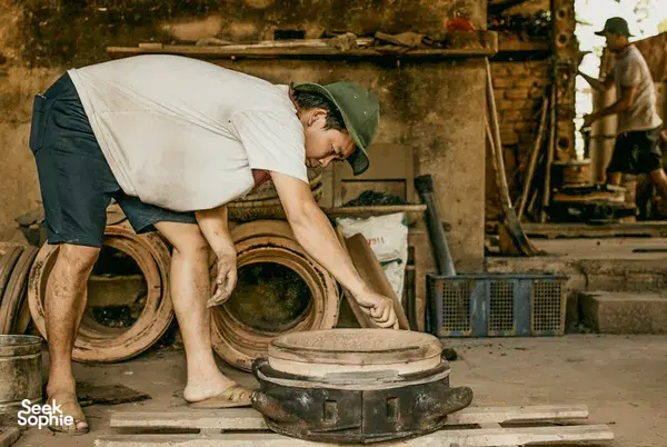 Man adjusting a metal cart in a roadside workshop during a Hoi An secret waterfall motorbike adventure route