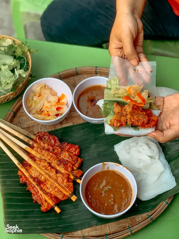 Kulit lumpia Vietnam sedang dirakit dengan saus cocolan dan sate panggang di Chan Dat Living Room, Hoi An