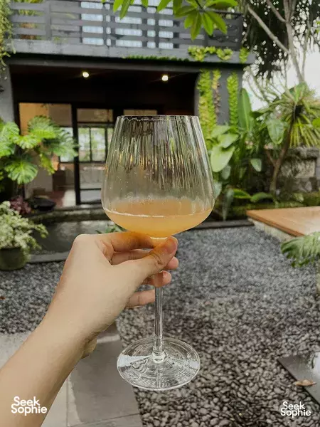 Hand holding a wine glass on a Balinese villa patio with rainforest foliage in Singapore, for private dining Singapore moments