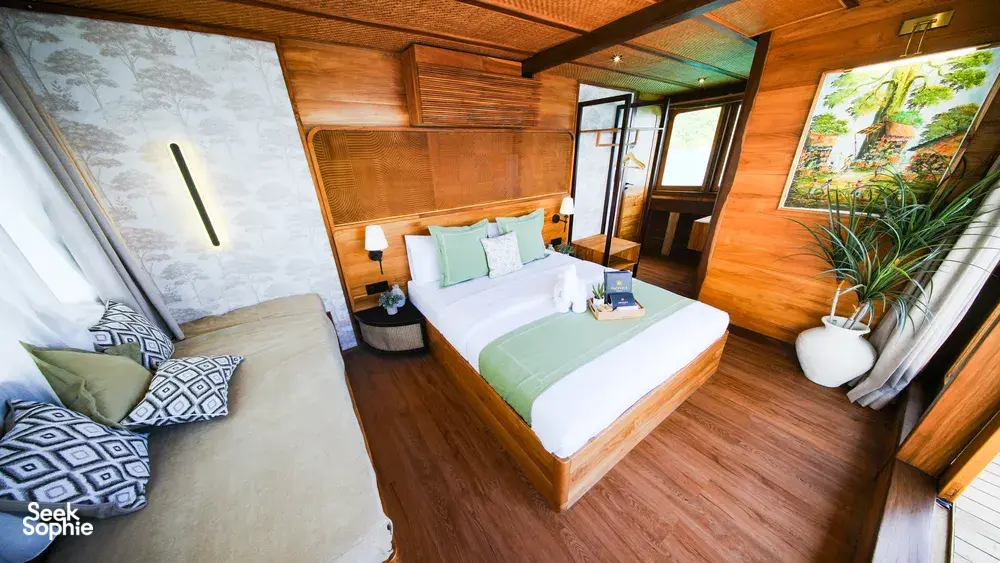 Luxurious phinisi bedroom with twin beds, green throw and sea-view windows on a 3D2N Komodo cruise in Labuan Bajo