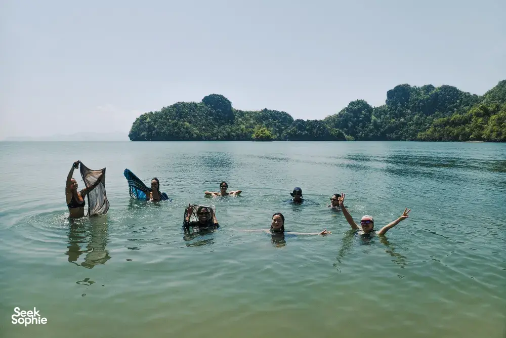 Bicycle Day Langkawi cyclists cool off with a swim in shallow water on Langkawi, surrounded by mangrove-lined islands