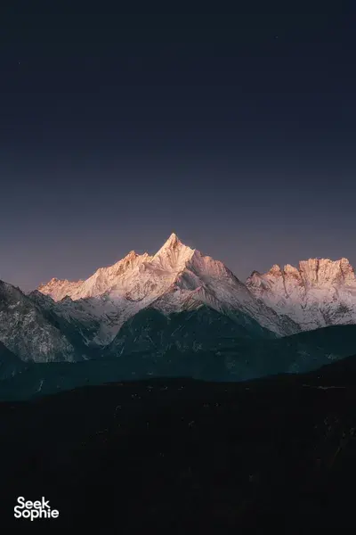 Star-filled night sky over Meili Snow Mountain as dawn light warms the snowy ridges on a 2D2N trek from Shangri-La
