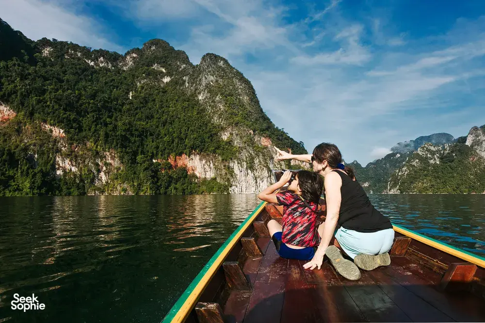 Family on a long-tail boat gazing at limestone karsts across the lake at Khao Sok Riverside Cottages, Cheow Lan Lake