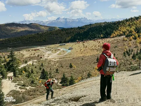 Hiker with a backpack overlooking a turquoise alpine lake basin in Shangri-La during the 2D1N trek towards Tiger Leaping Gorge
