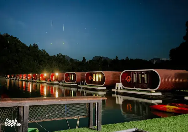 Nighttime view of joined rowboats with glowing lanterns on still water, moored near jungle-covered hills in Khao Sok — Khao Sok National Park