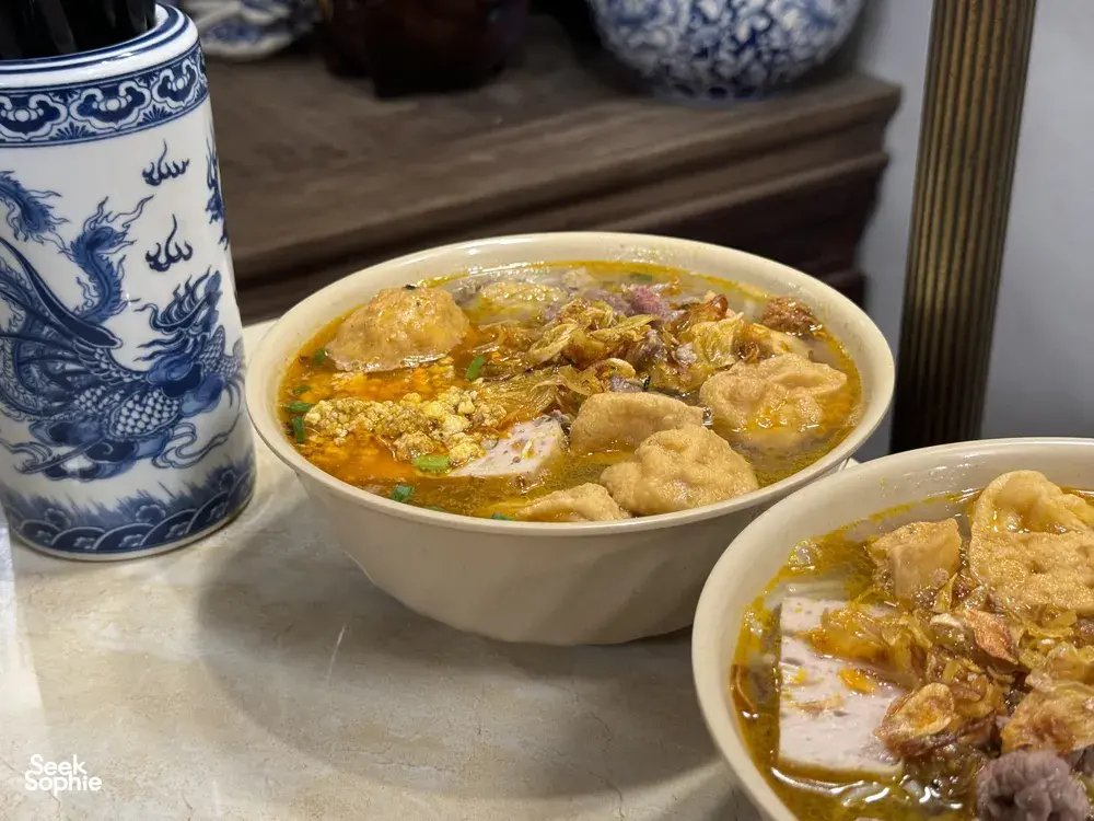 Two bowls of savoury Vietnamese soup with meat and herbs on a table during a Hanoi street food adventure