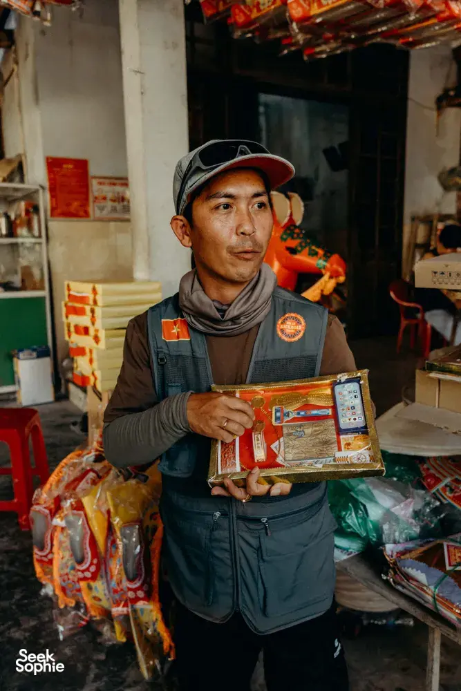 Tuyen Vu dari Hoi An Backroad Tours mengangkat satu set camilan kotak di toko lingkungan saat berkunjung ke Hoi An