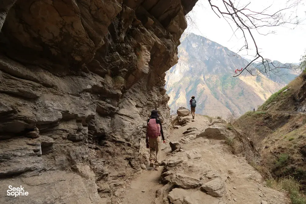 Hikers trek along a narrow rocky path on the High Trail of Tiger Leaping Gorge in Lijiang