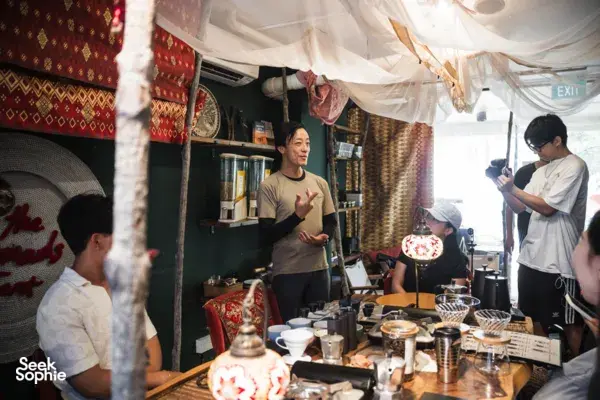 Guests listen as a host demonstrates coffee brewing with servers and equipment on a counter during brunch, workshops in Singapore