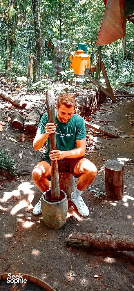Participant kneeling by a forest fire during the Lombok former loggers walk, preparing a drink at a cooking setup