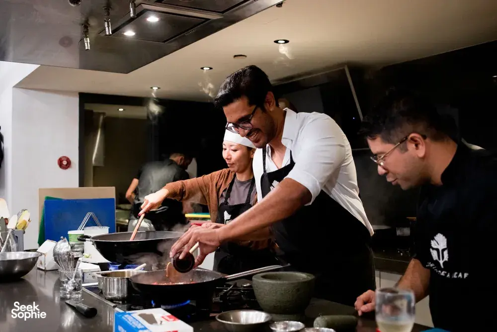 Cooking at saucepans in Singapore during the team local produce cooking challenge, chefs guide diners — workshops in Singapore