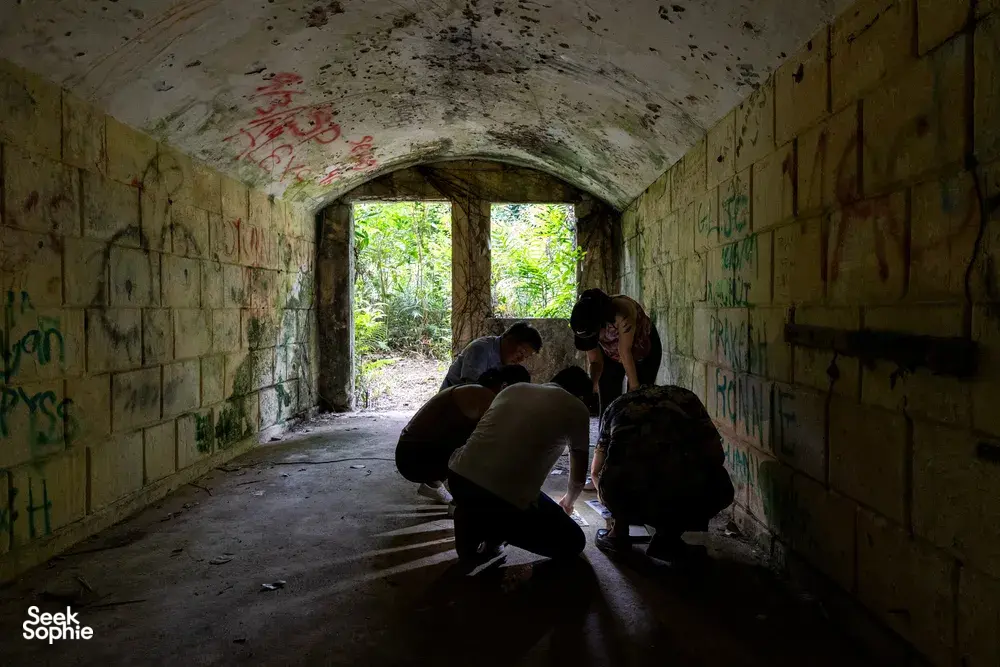 People explore a graffiti-lined tunnel and gather near the bright exit during Fort Serapong Discovery in Singapore hidden gems