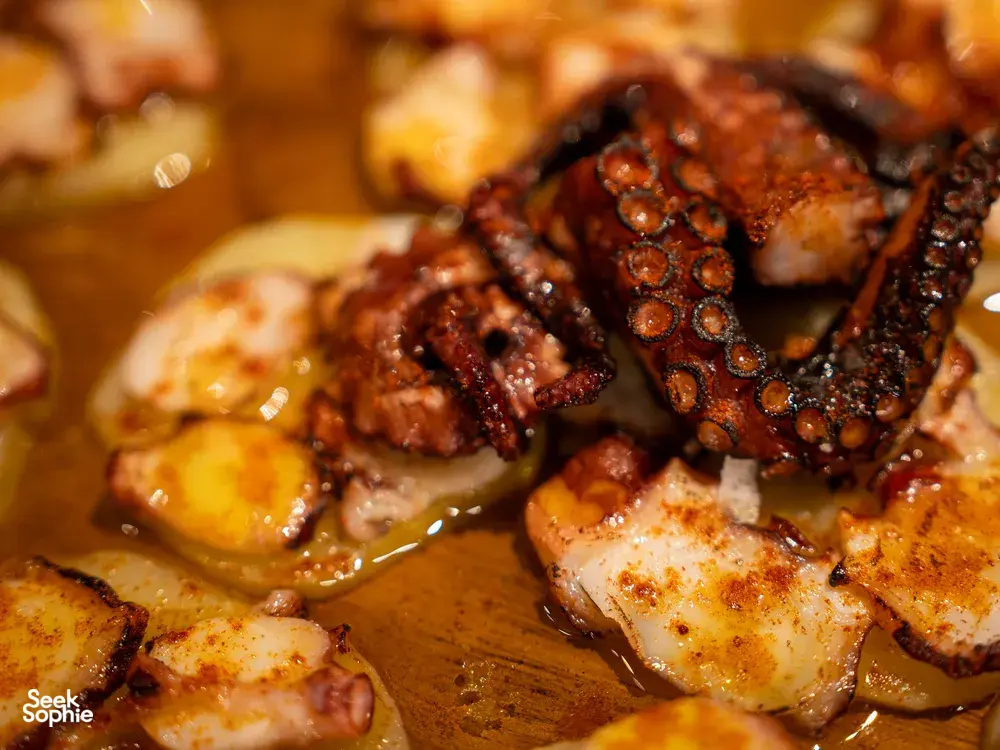 Seared octopus pieces with paprika in a pan, served at a Spanish tapas table in private dining Singapore