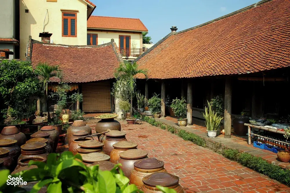 Courtyard of a traditional homestay in Duong Lam ancient village near Hanoi, lined with clay jars under tiled roofs