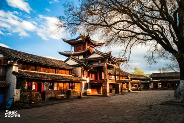 Red-and-wood traditional courtyard buildings with curved eaves and bare branches in Dali, Yunnan, part of a customised trip