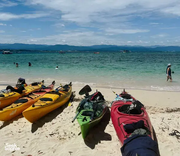 Kayaks in bright colours lined on a sandy beach at Kota Kinabalu for a kayak to hidden coves in Tunku Abdul Rahman Marine Park