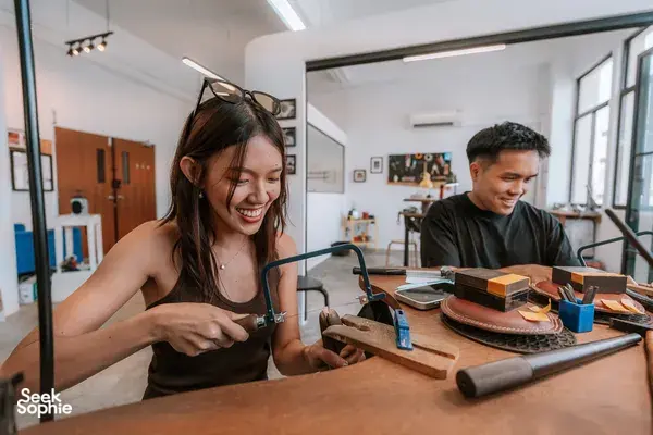Smiling couple shaping a silver ring at Fat Anvil Studios metalwork bench in Singapore, workshops in Singapore