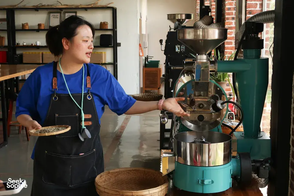 Seeker Yunnan Coffee Estate host in an apron operating a roaster machine in Lijiang’s coffee workshop