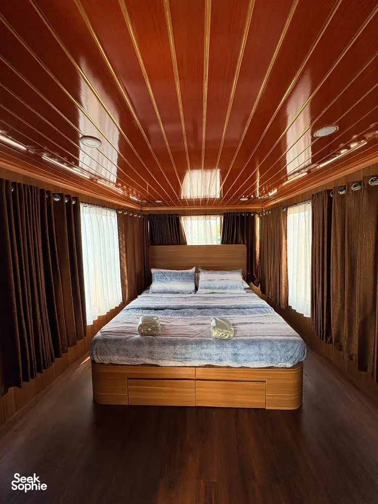 Air-conditioned houseboat cabin in Tanjung Puting, Pangkalan Bun, with neatly made double bed and curtained windows