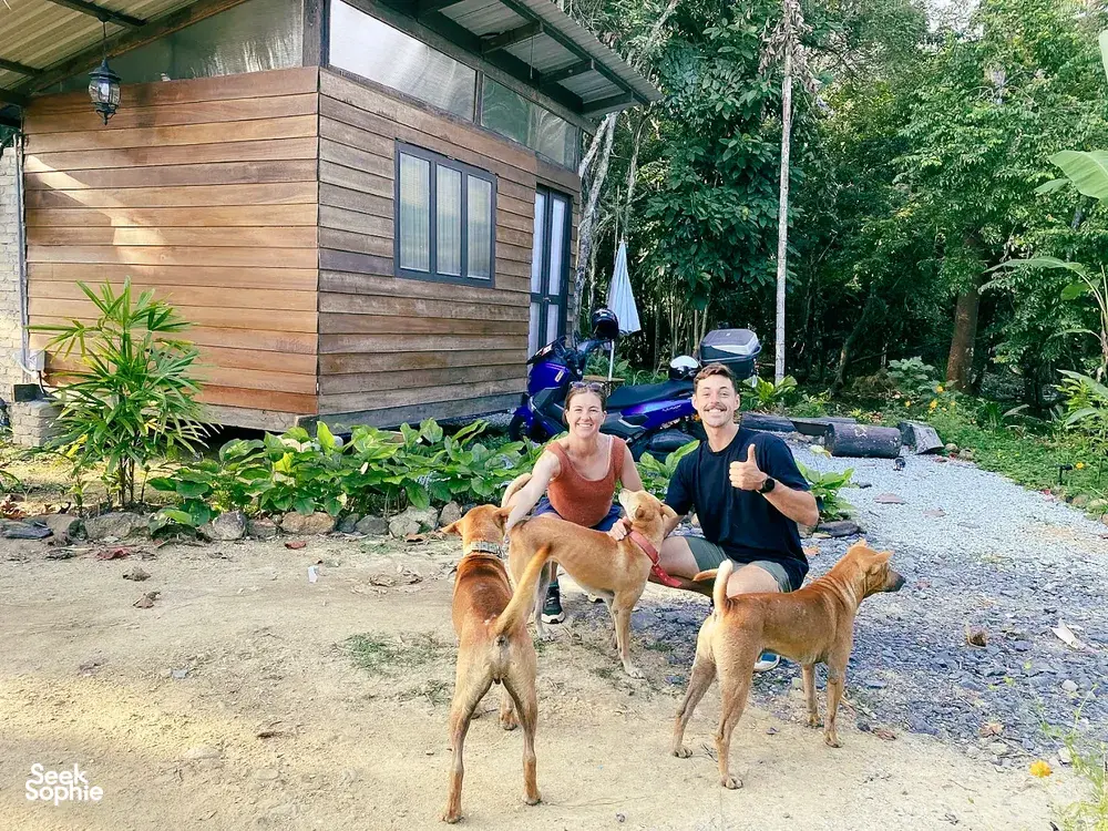 Kebun Lidstari permaculture farmstay in Langkawi: people smiling with dogs outside a wooden cabin in the greenery