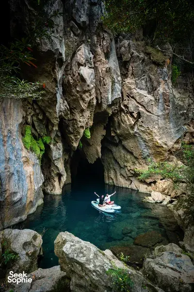 Kayak floats on turquoise water beneath towering limestone cliffs in Phong Nha, Vietnam during a cave exploration