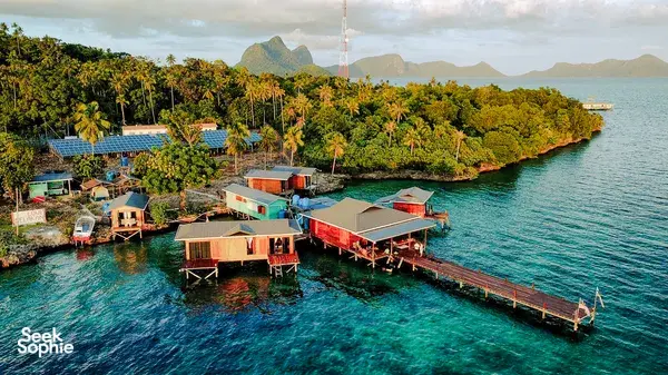 Aerial view of Luma Selakan sea lodge complex in Semporna with wooden platforms, boatsheds and jetty over the lagoon