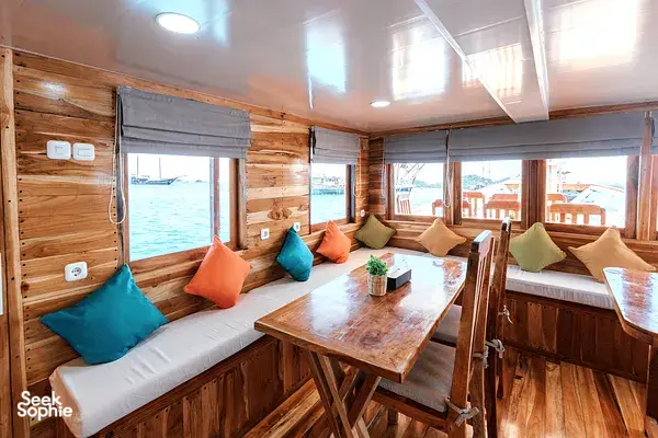 Wood-panel solo cabin with twin beds, pillows and a small table on a 4D3N Komodo dive liveaboard with ocean views on Komodo Island