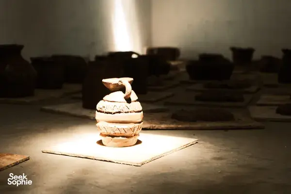 Terracotta clay pieces stacked on a work tile in a Yogyakarta pottery workshop, softly lit by a beam of sunlight
