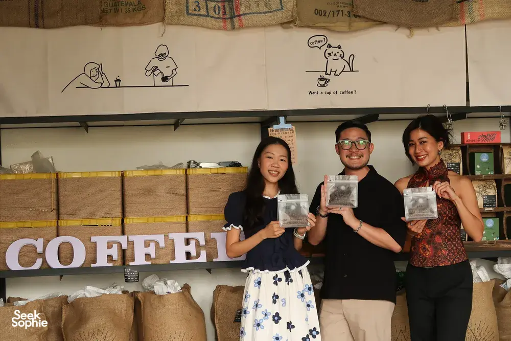 Seeker Yunnan Coffee Estate in Lijiang: visitors pose with packaged coffee samples at a coffee counter with signage