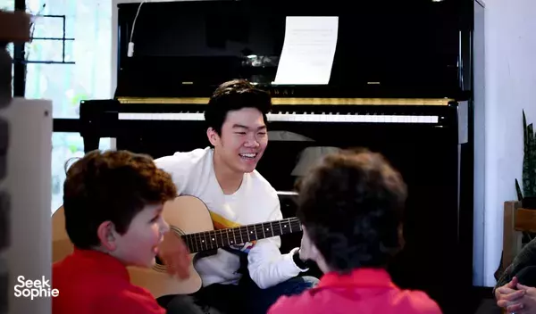 SmallGiant Music guitar teacher guiding children as they play acoustic notes during a music lesson workshops in Singapore