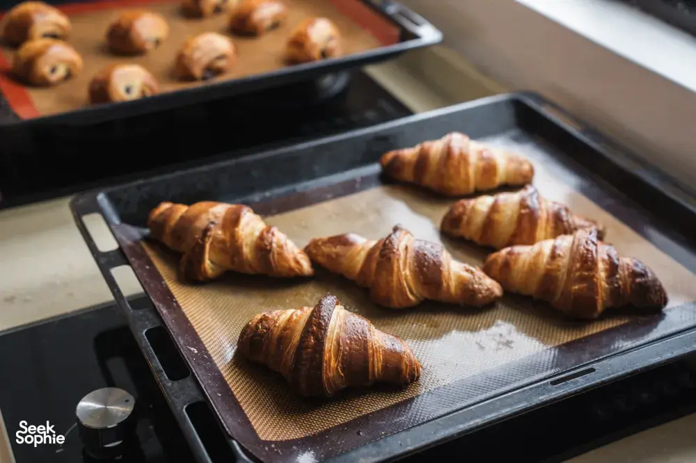 Baked croissants spaced on two oven trays, ready to leave the French Cooking Lab kitchen during a Singapore session