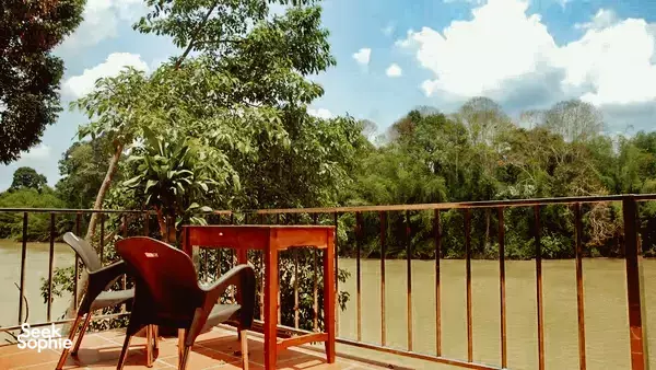 Balcony with two chairs and a small table overlooking a wide river and dense forest canopies in Cat Tien