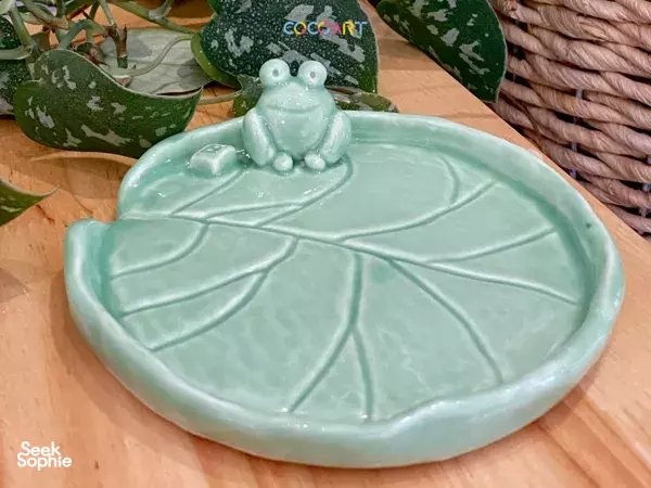 Frog-themed green ceramic dish shaped like a lily pad, with a small frog figurine, made in a Singapore studio workshops in Singapore
