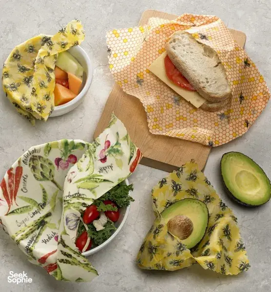 Reusable beeswax food wraps over bread and vegetables beside an avocado and bowl on a table in Singapore during workshops in Singapore