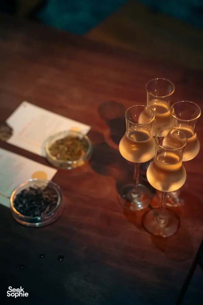 会安鸡尾酒之旅中，木桌上的品鉴卡旁摆着高脚杯盛装的金色鸡尾酒特写