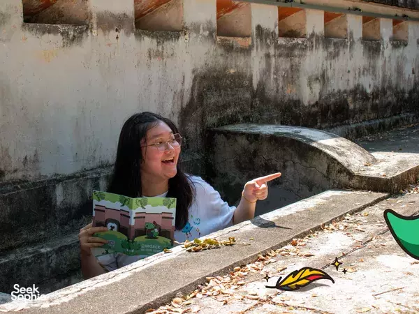 Solving puzzle clues while holding a story booklet at Fort Canning during an outdoor Puzzle Hunt in Singapore