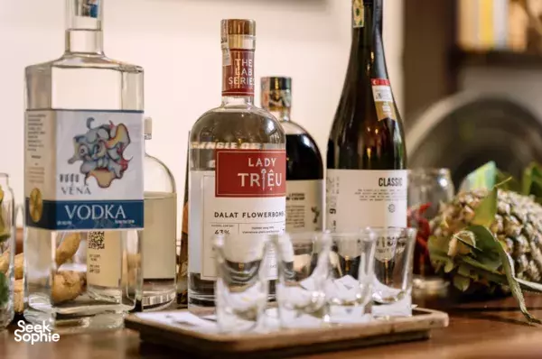 Close-up of labelled vodka and gin bottles with small tasting glasses on a tray during a gin tasting in Ho Chi Minh City