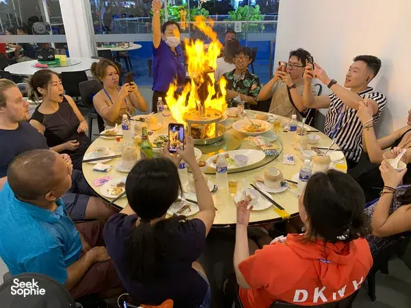 Group gathered around a flame-centred table in a restaurant during the Geylang private night walk in Singapore — Singapore hidden gems