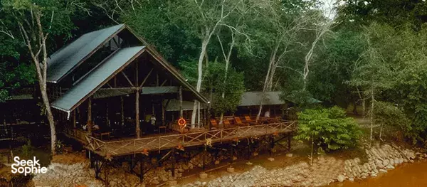 Misty dusk view of a decked riverside lodge on stilts by the water at Scenic Riverside Resort, Sandakan, Kinabatangan River