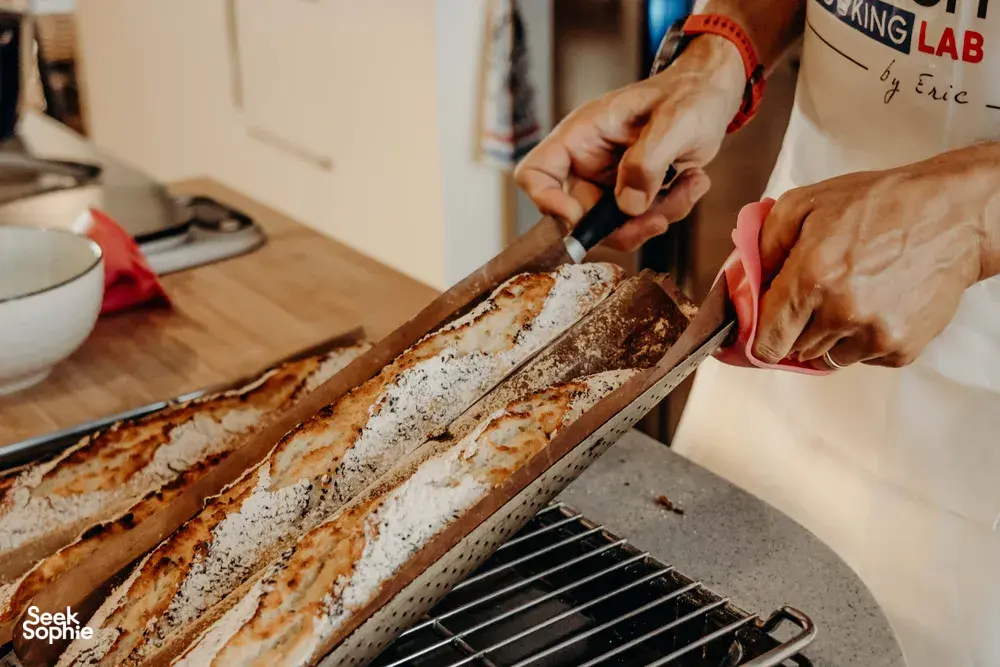 French baguettes ready on a tray as hands cut fresh loaves in a cosy Singapore loft — workshops in Singapore