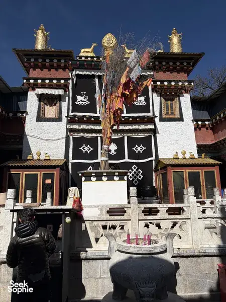 Decorated Tibetan courtyard doorway with prayer flags at Mission Liotard in Shangri-La, Yunnan, offering a cultural resting stop
