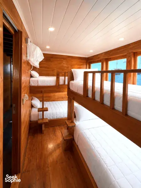 Wooden phinisi cabin with twin berths and panoramic windows for a 3D2N shared Komodo cruise, Komodo Island