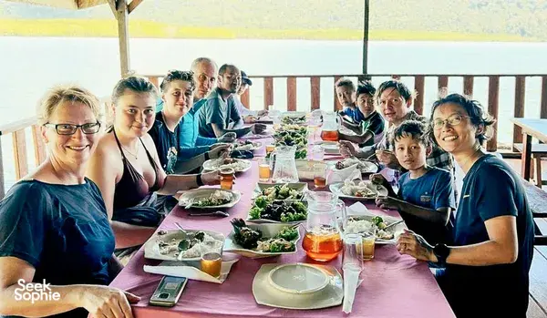Meal shared by travellers at a long table on the deck during a Langkawi trip for mangroves, caves and island swimming
