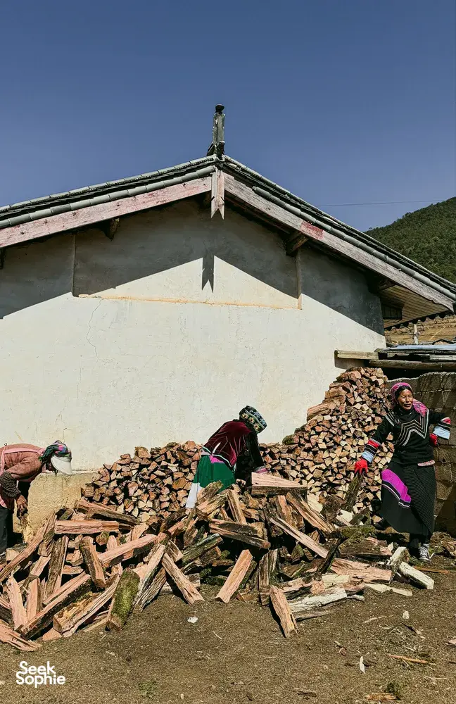 Traditionally dressed villagers carrying firewood at a countryside guesthouse in Lijiang during a Yi & Naxi village trek